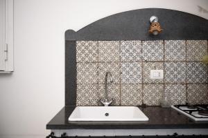 a kitchen with a sink and a tiled wall at Palazzo dello Spagnolo Suite in Naples