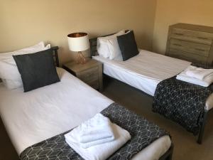 um quarto com duas camas e um candeeiro sobre uma mesa em Blue Sky Apartments @Wallis Square, Farnborough em Farnborough