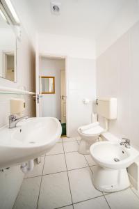 a white bathroom with two sinks and a toilet at Regia Panzió in Halászi