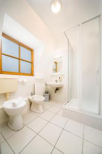 La salle de bains blanche est pourvue d'une douche et de toilettes. dans l'établissement Regia Panzió, à Halászi