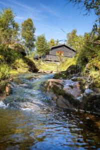 ein Fluss mit einem Haus im Hintergrund und einem Bach in der Unterkunft Voss Waterfalls - Private mountain cabin & Traveller Award Winner! in Vossevangen