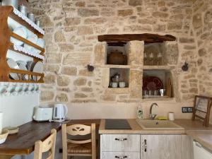 a kitchen with a stone wall with a counter and a sink at Little cellar in Chora Folegandros