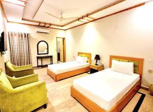 ein Hotelzimmer mit 2 Betten und einem Stuhl in der Unterkunft Royal Continental Hotel in Lahore