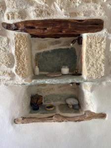 a shelf on a stone wall with some items on it at Little cellar in Chora Folegandros