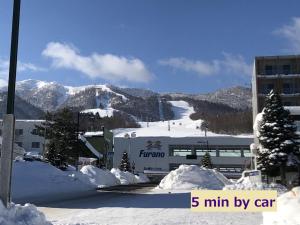 Furano Yayoi-house　 في فورانو: جبل مغطى بالثلج مع مبنى ومنحدر التزلج