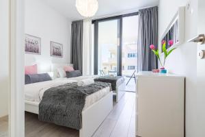 a white bedroom with two beds and a window at Aziza 1- Bedroom Apartment in Larnaca in Larnaka