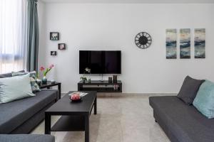 a living room with a couch and a tv at Aziza 1- Bedroom Apartment in Larnaca in Larnaka