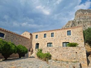 a stone building with a mountain in the background at Lazareto Hotel in Monemvasia