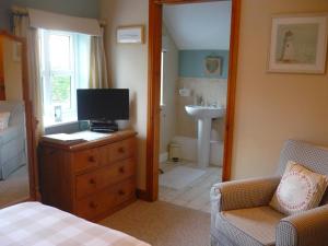 1 dormitorio con tocador con TV y baño en White Cottage Bed and Breakfast, en Seisdon