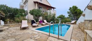 a swimming pool with chairs and a house at Apartment Nikola in Jelsa