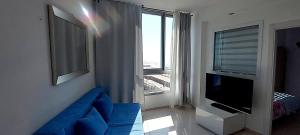 a living room with a blue couch and a large window at Hotel Apartment Short Term Tel Aviv Bat Yam 5 in Bat Yam