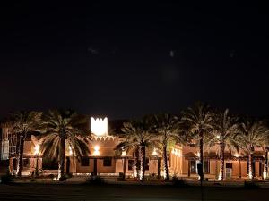 un edificio con palme di fronte ad esso di notte di Al Artaa Resort a Liwa