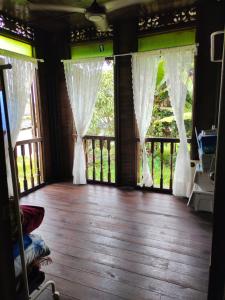 Habitación con ventanas con cortinas y suelo de madera. en Homestay Kampung Den en Kampong Jimah