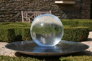a glass ball sitting on a plate in a garden at Whatley Manor in Malmesbury