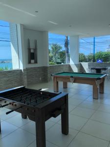 2 mesas de ping pong en una habitación con ventanas en Apartamento peracanga com vista para o mar en Guarapari