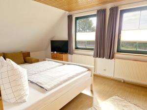 a bedroom with a bed and a tv and two windows at Ferienwohnung Rohlffs Stolpe auf Usedom in Stolpe auf Usedom