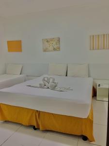 Cama blanca en habitación con sofá en Pousada Marahub, en Maragogi