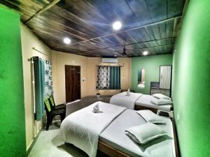 a room with two beds and a green wall at Resort Gorumara Riverside in Lataguri