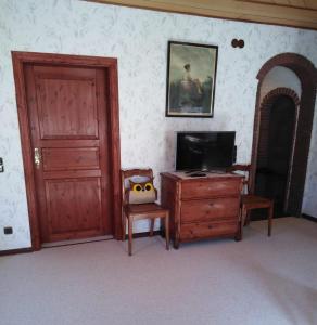 a room with a door and a chair and a television at Haus Bindseil - Ferienwohnung im OG, links in Altenau