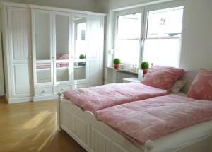 Schlafzimmer mit einem Bett mit rosa Bettwäsche und einem Fenster in der Unterkunft Ferienwohnung Rheingold in Andernach