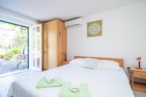 a bedroom with a white bed with towels on it at Apartments Lidija in Zaton