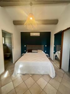 a bedroom with a large white bed and a chandelier at "La villa Mariam" Jacuzzi Jardin in Fourques