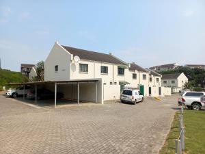 a large white building with cars parked in a parking lot at 61 Settler Sands - Beach apartment in Port Alfred