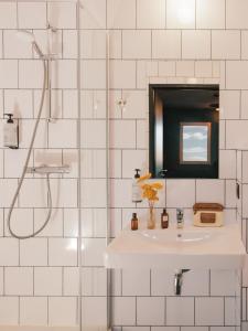a white tiled bathroom with a sink and a shower at Eklo Hotels Toulouse Cartoucherie Zénith in Toulouse