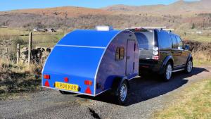 a blue van with a trailer parked on a road at Darwin Teardrop Caravan for Hire from ElectricExplorers in Hawkshead