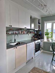 una cocina con armarios blancos y fregadero en Koselig leilighet midt i sentrum en Skjervøy