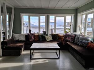 sala de estar con sofá marrón y ventanas en Koselig leilighet midt i sentrum, en Skjervøy