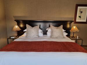 a large bed with a red blanket and pillows at Bass Lake Country Lodge in Pretoria