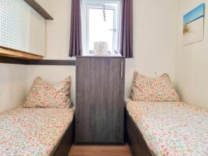 2 Betten in einem kleinen Zimmer mit Fenster in der Unterkunft Chalet Serooskerke SE09 in Serooskerke