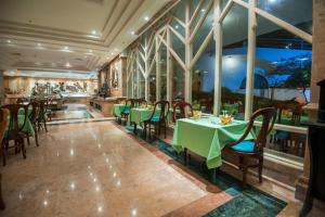 een restaurant met groene tafels, stoelen en ramen bij Shams Safaga Resort in Hurghada