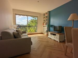 a living room with a couch and a television at Les Tennis - Superbe appartement avec parking in Houlgate