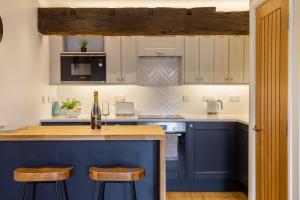 a kitchen with blue cabinets and a counter with stools at Luxury Apartment Woodsmill View - on the river - with balcony - Recently refurbished in York