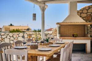 uma mesa de madeira com cadeiras e copos de vinho num pátio em Ioanna Château - Luxury Stone Villa em Maryiés