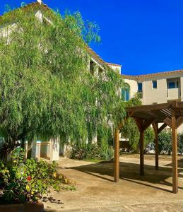 un padiglione di fronte a un edificio con un albero di Résidence Les Pavillons du Golfe a Favone