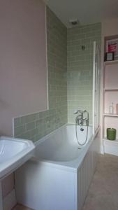 a bath tub in a bathroom with green tiles at Grocer John's. The heart of the old town in Padstow