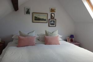 1 dormitorio con cama blanca y almohadas rosas en Grocer John's. The heart of the old town, en Padstow
