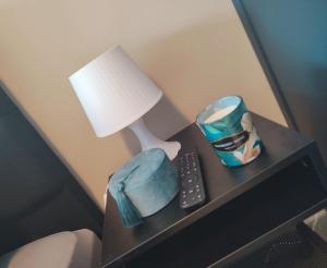 a nightstand with a lamp and a remote control at L auberge de l Entre Potes- Bolia in Ath