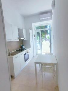 cocina con mesa, sillas y mesa blancas en B&B Lido Apartament 10B, en Civitanova Marche