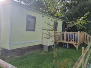 a green house with a porch and a deck at Glamping Hut - Riverview 5 in Garthbeibio