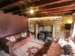 a living room with leather couches and a stone fireplace at Bute Cottage in Pickering