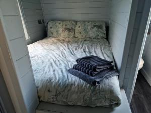 a small bed in a small room with towels on it at Glamping Hut - Sleeps 2 hot tub & parking in Garthbeibio