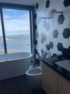 a bathroom with a tub and a toilet and a window at Citadine Ha Long luxury (Ocean View) in Ha Long