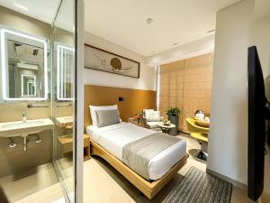 a bedroom with a bed and a bathroom with a sink at Morvee Hotels Alipore Kolkata in Kolkata