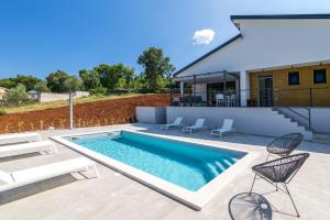 una piscina con sedie e una casa di Villa Bellavu a Rakalj