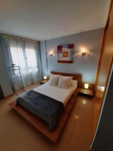 um quarto com uma cama grande com lençóis brancos e almofadas em APARTAMENTO CORTEGADA em Vilagarcía de Arousa