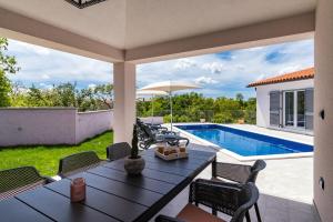 a patio with a table and chairs and a swimming pool at Villa NaNa in Orbanići